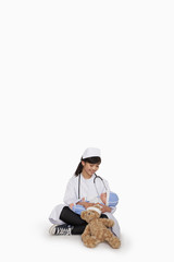 Girl dressed up as doctor with teddy bear and doll