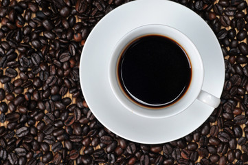 Cup of coffee on coffee beans background. top view