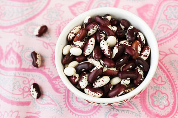 One bowl with red and white beans on pink tablecloth