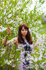 brunette girl standing on nature around blooming cherry tree wit