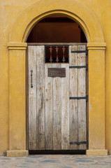 Antique wooden door on yellow cement wall
