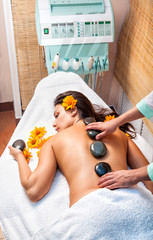 Stone therapy. Woman getting a hot stone massage in spa salon