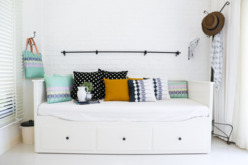 Colorful pillows on a sofa with white brick wall in background