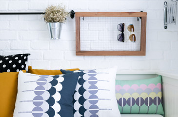 Colorful pillows on a sofa with white brick wall in background
