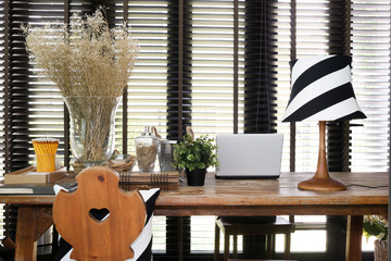 Wooden working table with a laptop, vintage lamp and pillow