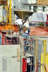 ouvrier maçon utiliant une benne à béton