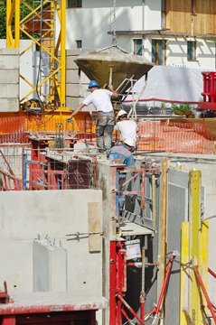 ouvrier ma&ccedil;on utilisant une benne &agrave; b&eacute;ton