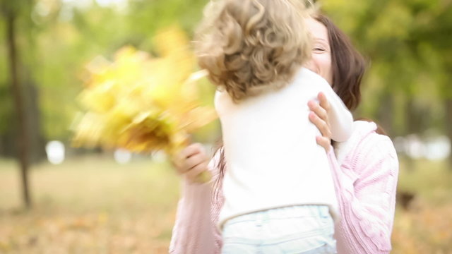 Happy child kissing her mother in autumn park
