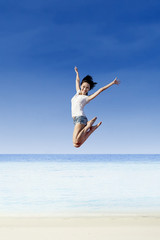 Asian girl jump at white sand beach