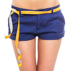 Closeup of fit female hips in blue shorts with measuring tape