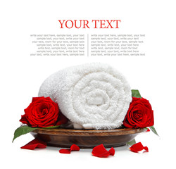Rolled white towel and roses and rose petals