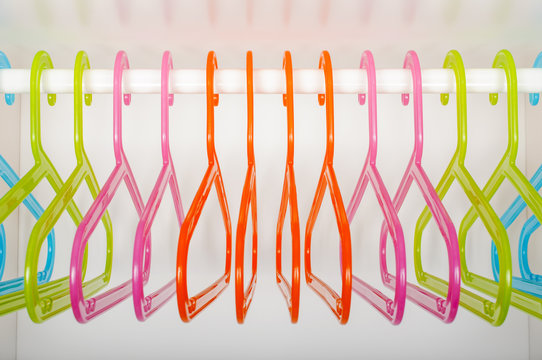 Colored hangers on a rod in a wardrobe