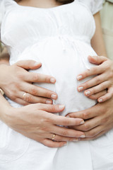 Closeup of hands of pregnant wife and her husband