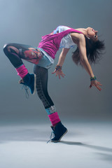 Woman in pink grunge clothes dancing in a studio.