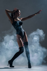 Fototapeta na wymiar Modern style dancer posing on a studio grey background in fog