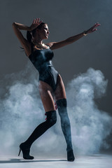 Modern style dancer posing on a studio grey background in fog