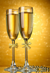 Two glasses of champagne on bright background with lights