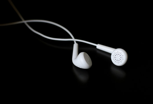 White Earphones On Black Reflective Surface