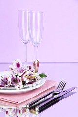 Festive table setting with flowers on lilac background
