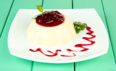 Panna Cotta with raspberry sauce, on color wooden background