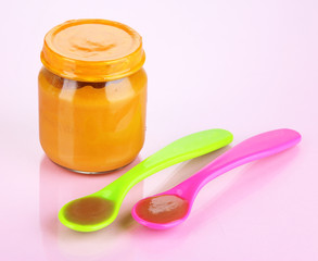 Baby food with weaning spoons on purple background