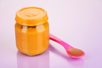 Baby food with weaning spoon on purple background