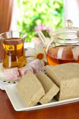 Tasty halva with tea on table in room