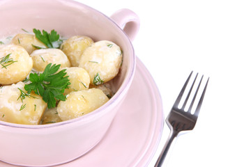 Tender young potatoes with sour cream and herbs in pan isolated