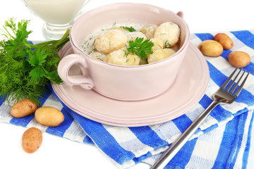 Tender young potatoes with sour cream and herbs in pan isolated
