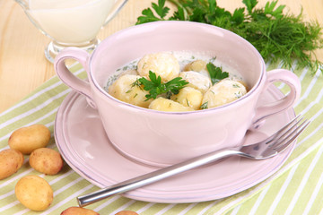 Tender young potatoes with sour cream and herbs in pan