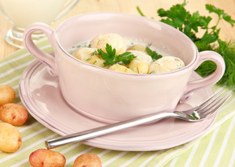 Tender young potatoes with sour cream and herbs in pan