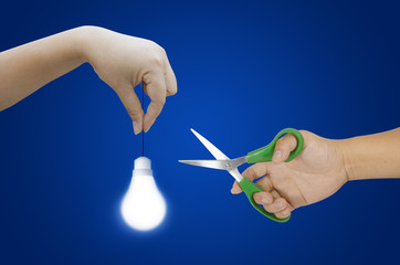 hand holding light bulb and scissors