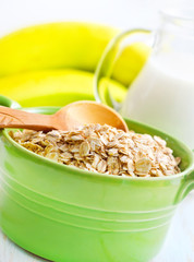 Oat flakes in the green bowl with banana and milk