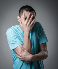 Fototapeta premium Desperate young man covering with his head in his hands