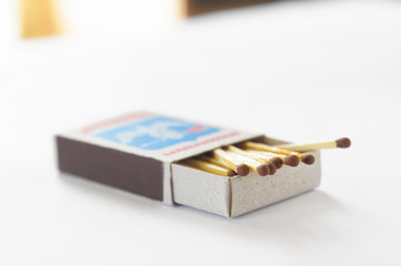 Open matchbox with some matches on a white table