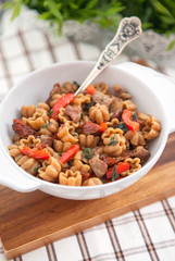 Curly pasta with meat and vegetables on wooden board