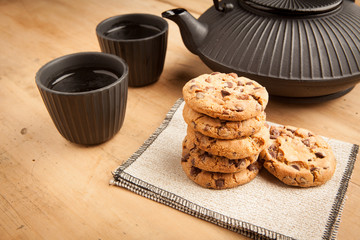 Chocolate biscuits with teapot and mugs, wooden background