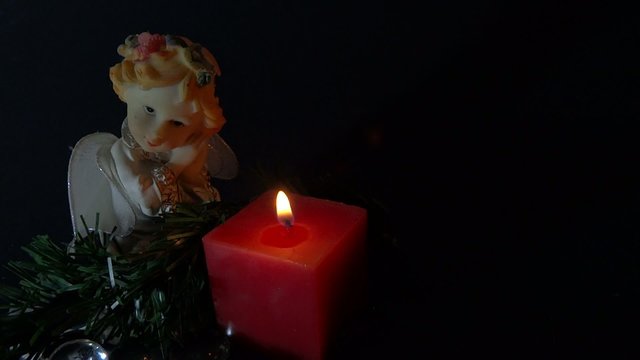 person igniting a candle with angel figurine