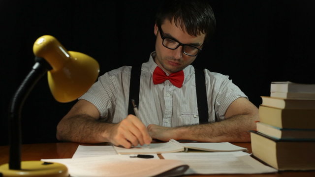 Serious nerd man writing in home office at night