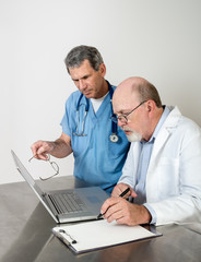Fototapeta na wymiar Two Senior Doctors at Laptop Computer Talking