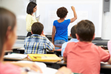 Female Student Writing Answer On Whiteboard