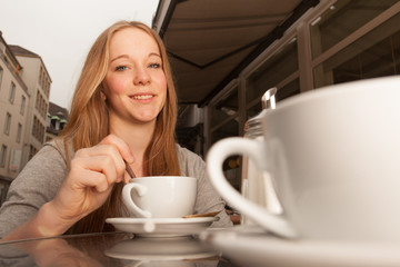 Junge Dame rührt Kaffee / Tee um