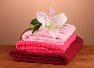 Obraz na płótnie Canvas stack of towels with pink lily on a brown background