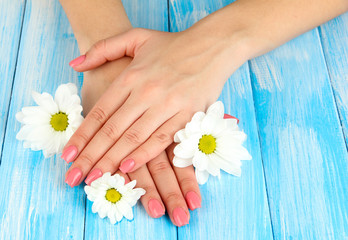 Obraz na płótnie Canvas Woman hands with pink manicure and flowers, on color background