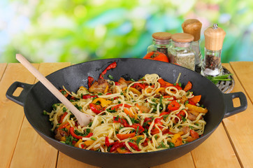Noodles with vegetables on wok on nature background background