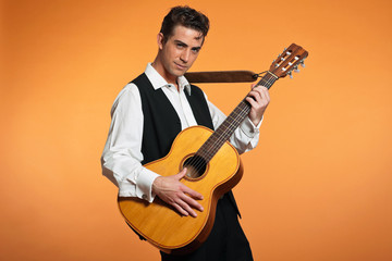 Retro country male guitar player wearing black suit. Studio shot