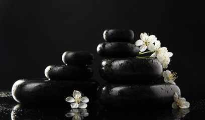 Fototapeta premium Kamienie Spa i białe kwiaty na czarnym tle