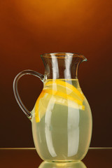Lemonade in pitcher on orange background