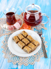 Sweet baklava on plate with tea on table