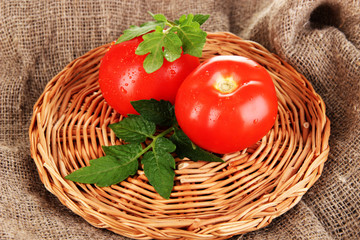 Fresh tomatoes on wicker mat on sackcloth background